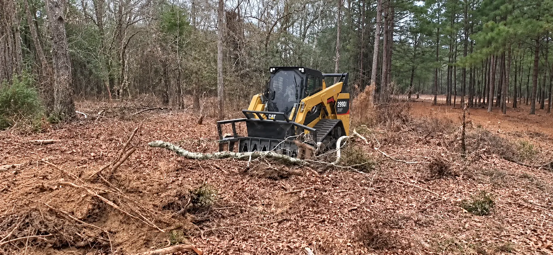 Tracked loader clearing land with a grapple attachment